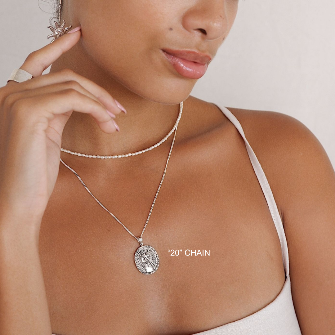 Woman wearing a silver necklace with a pendant, close-up on a neutral background