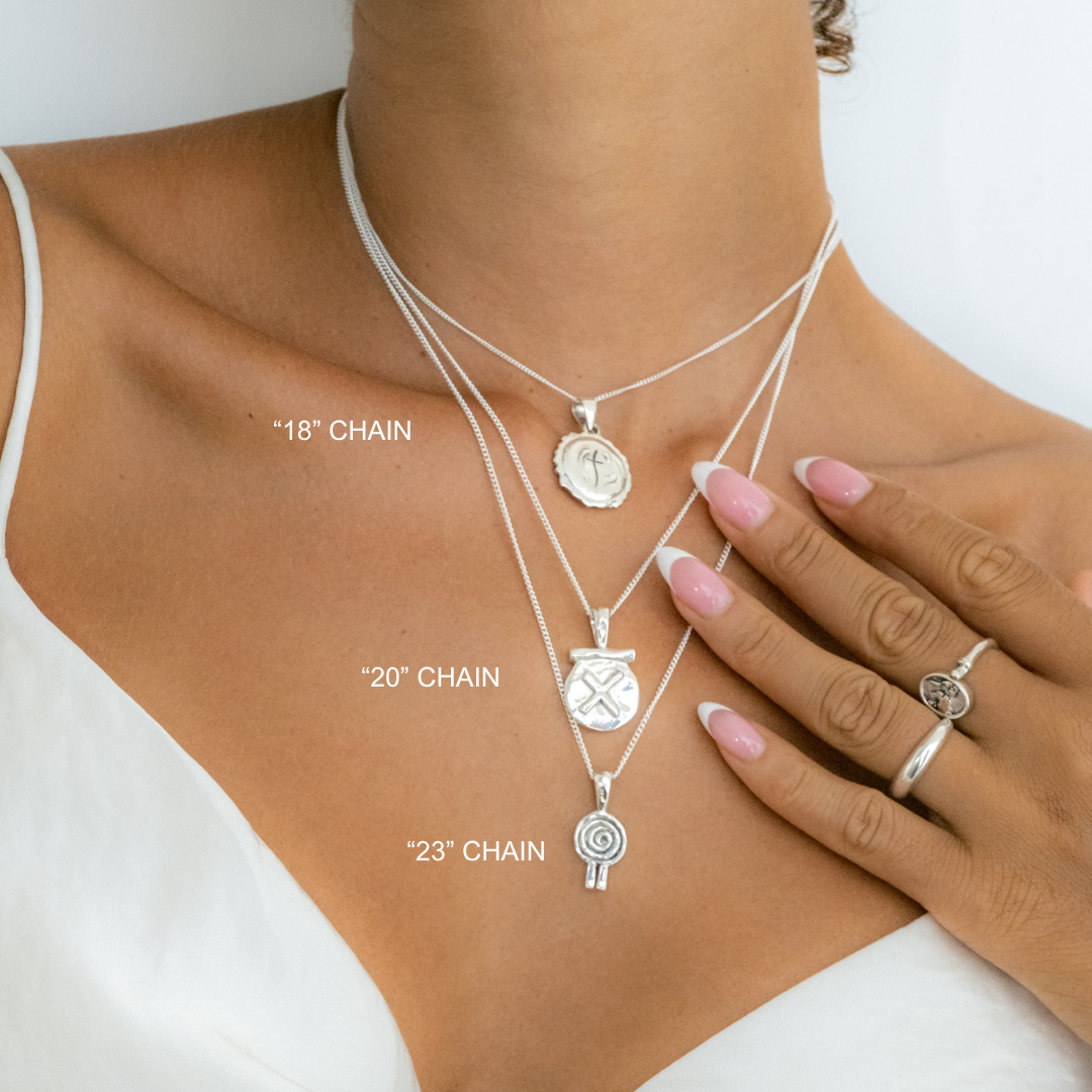 Silver necklaces with various pendants on a person's neck, labeled with chain lengths.