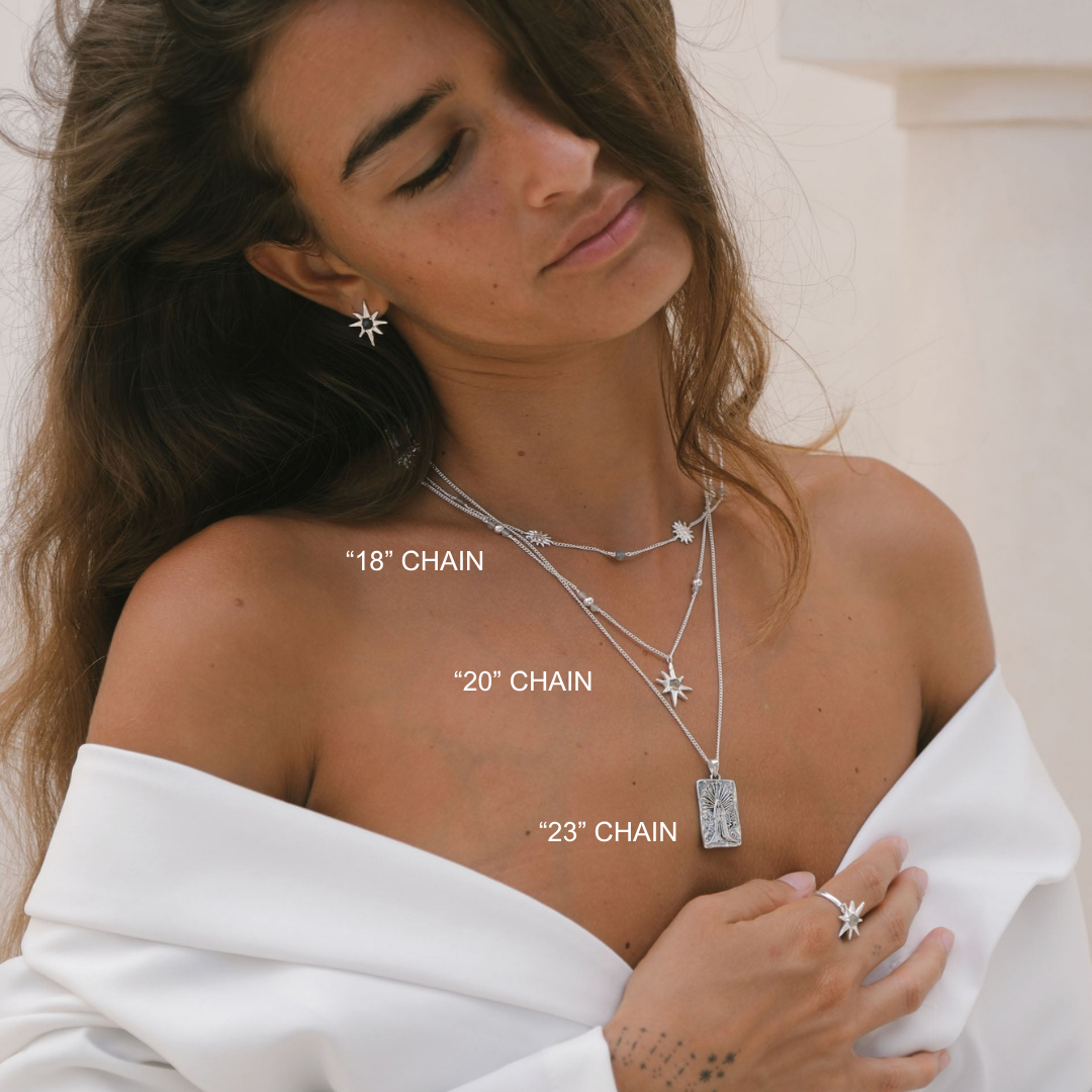 Woman wearing layered necklaces with chain length labels on a neutral background