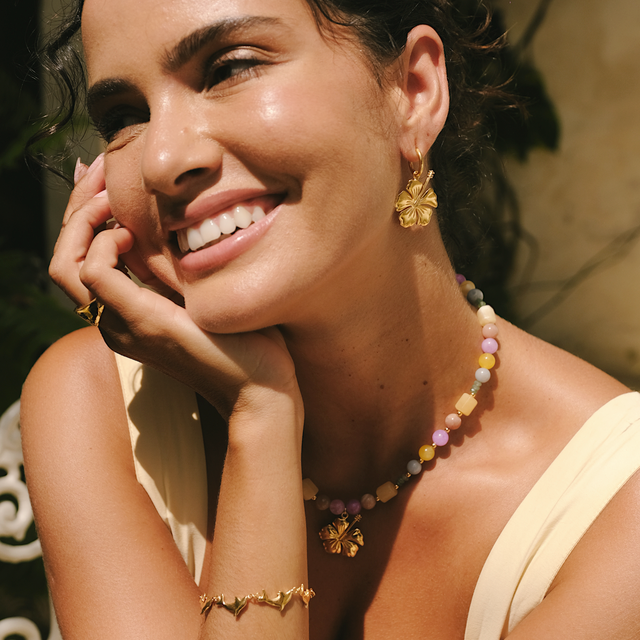 Woman wearing gold jewelry with a blurred background