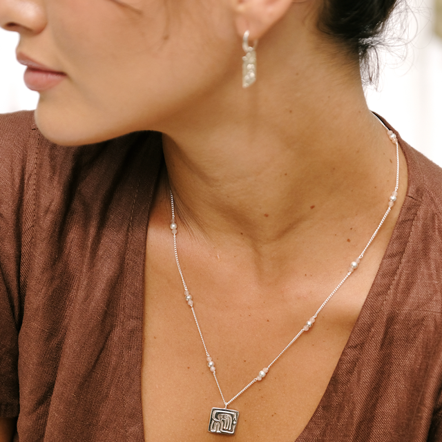 Close-up of a woman in a cocoa dress wearing a silver Tahnee necklace
