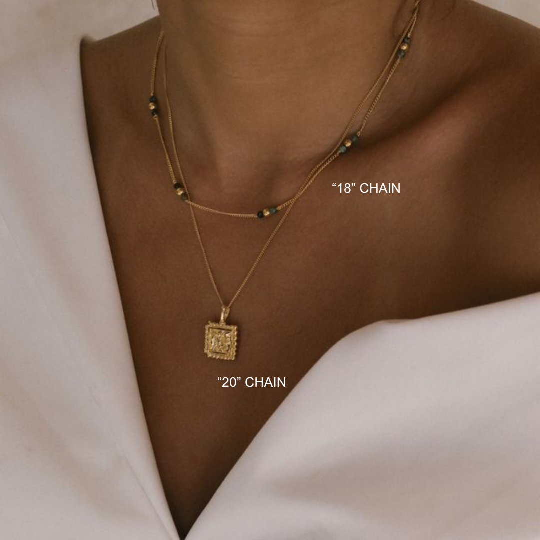 Gold necklace with two chain lengths on a neutral background