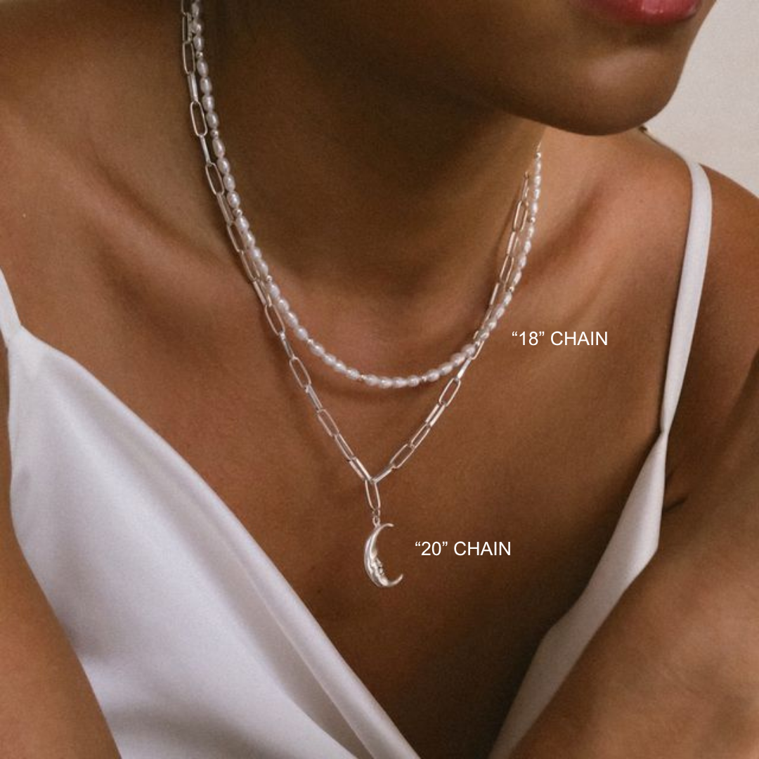 Close-up of a woman wearing two silver chain necklaces with measurements labeled.