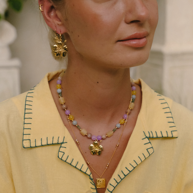 Woman in bright daylight wearing gold earrings and necklace by luna rose