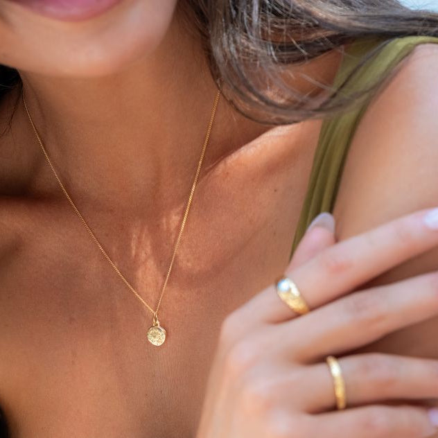 Woman showcasing a mini St. Christopher pendant on a fine chain