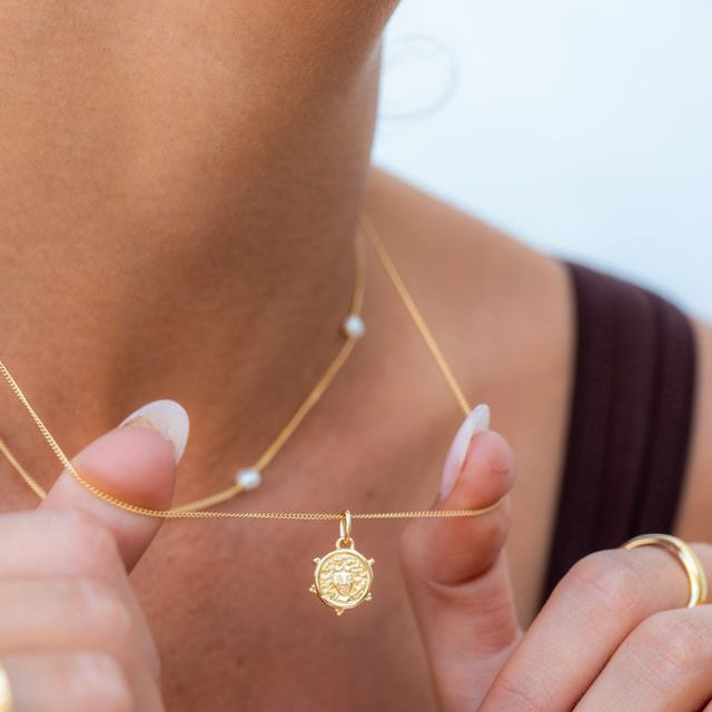 Woman wearing a minimalist mini Medusa necklace for an elegant look