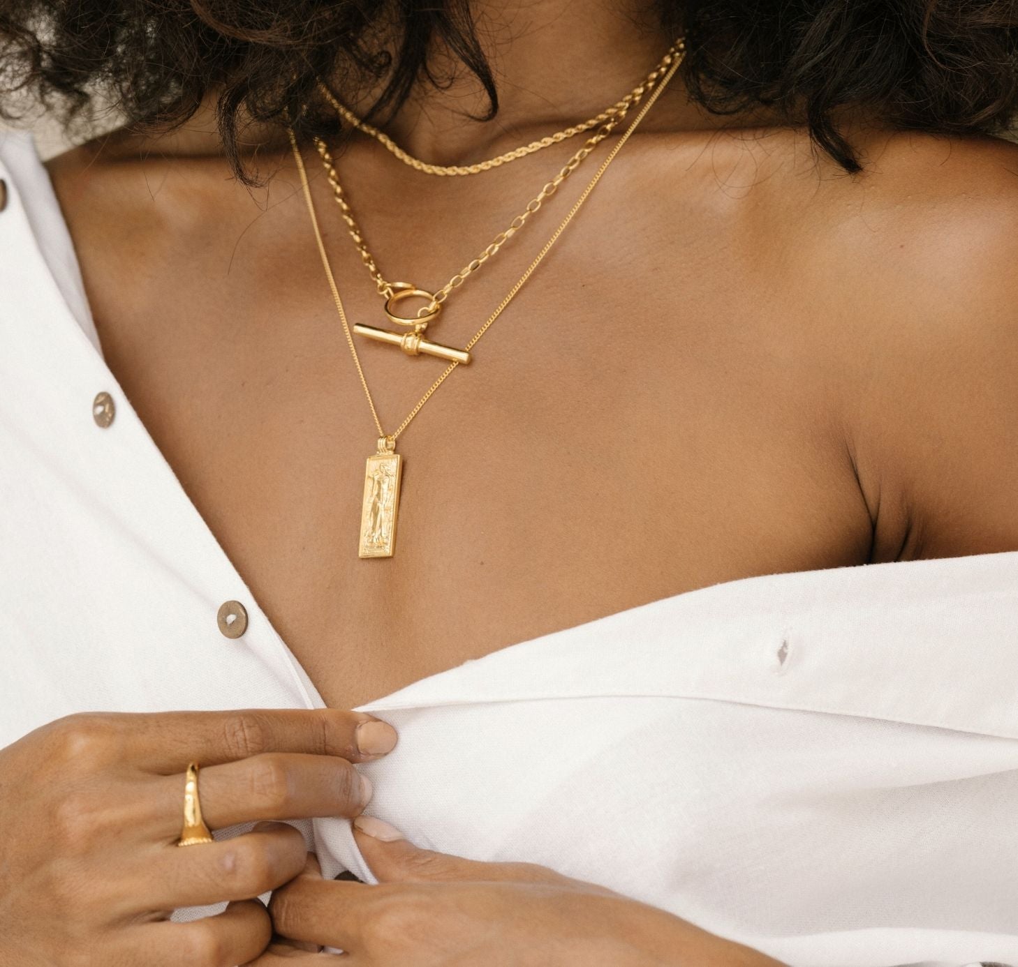a woman with  open shoulder shirts wearing Freyja necklace gold, FOB necklace and Rhode island necklace gold 