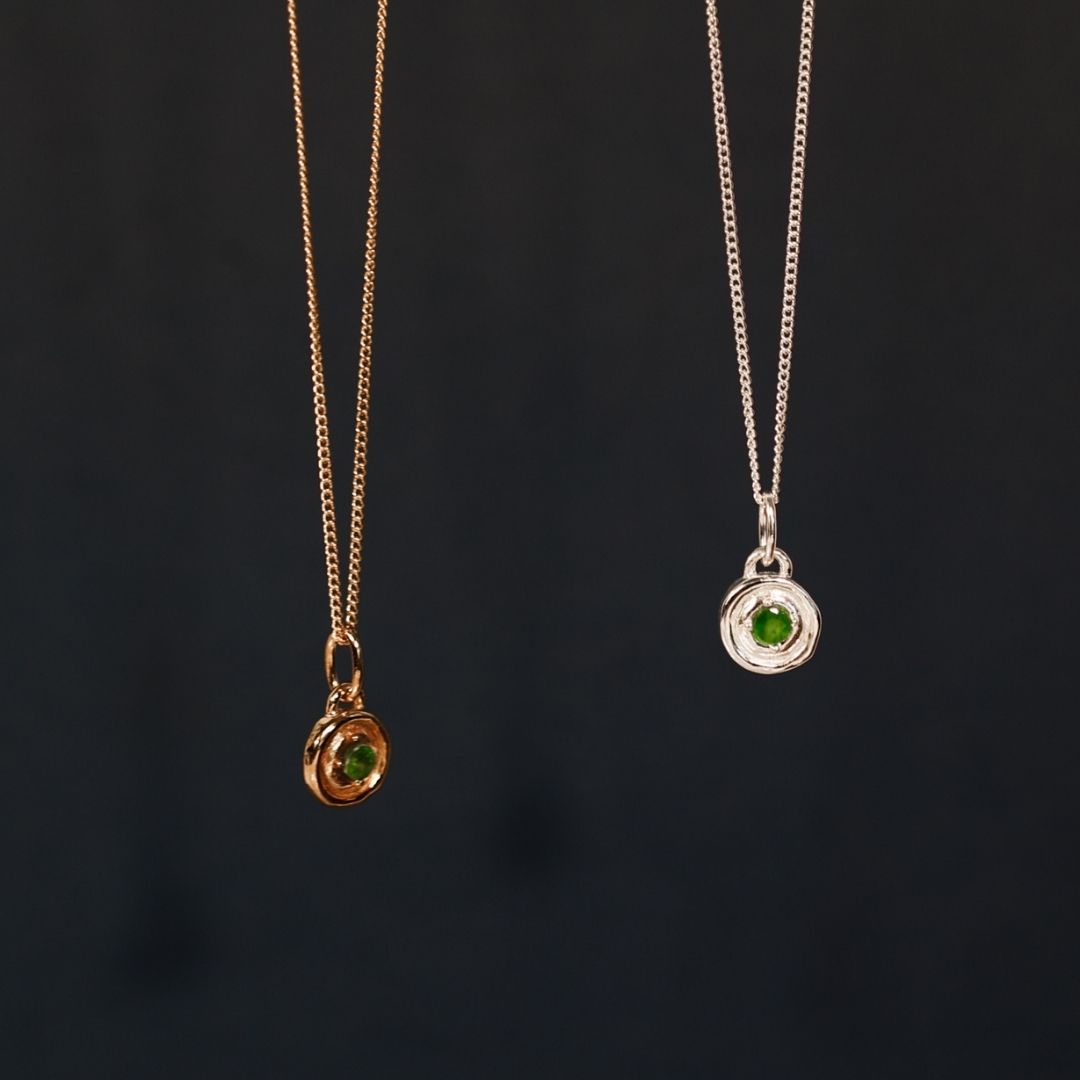 Two necklaces with green gemstones on a dark background