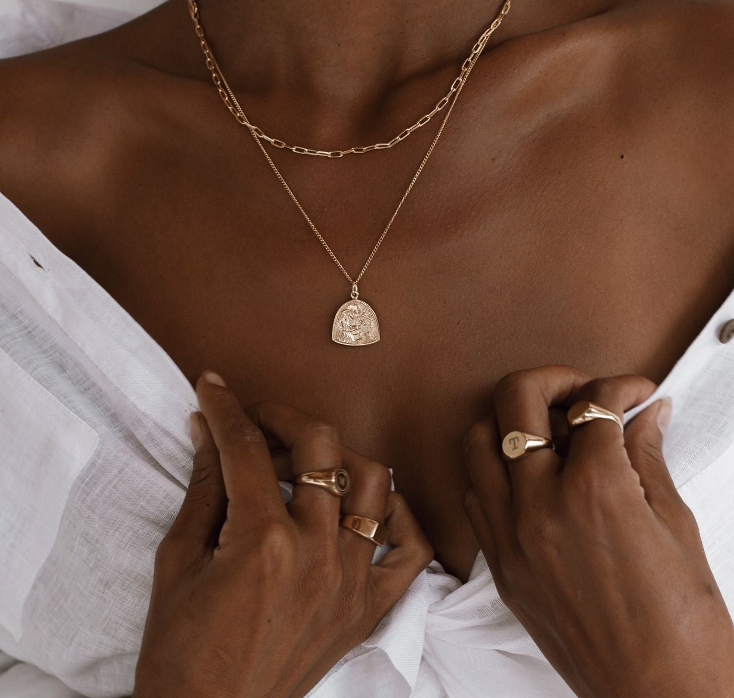 a woman wearing rings gold on her finger and necklaces gold 