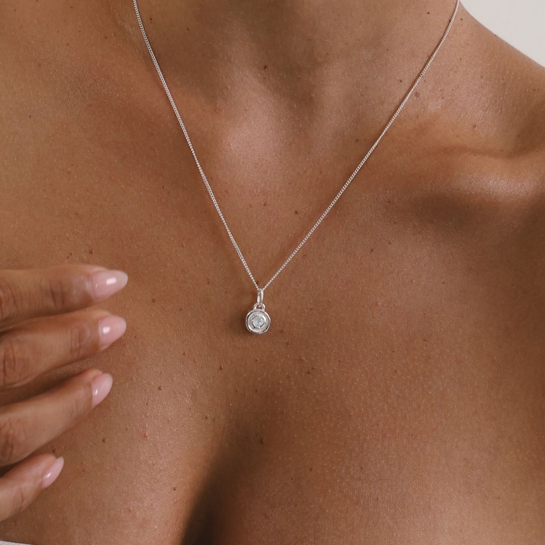 Silver necklace with a pendant on a person's neck