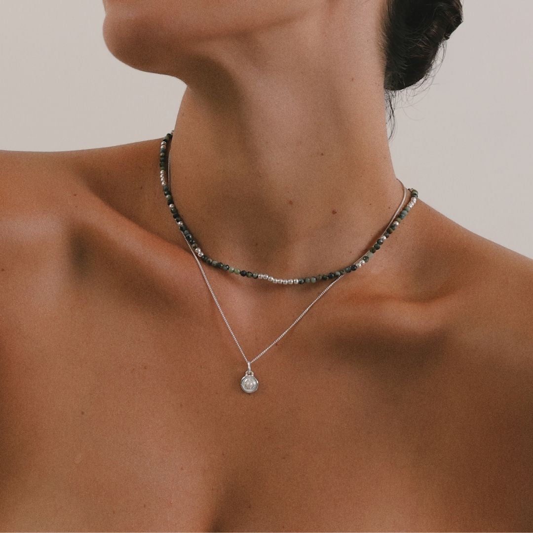 Necklace with a pendant on a person against a neutral background