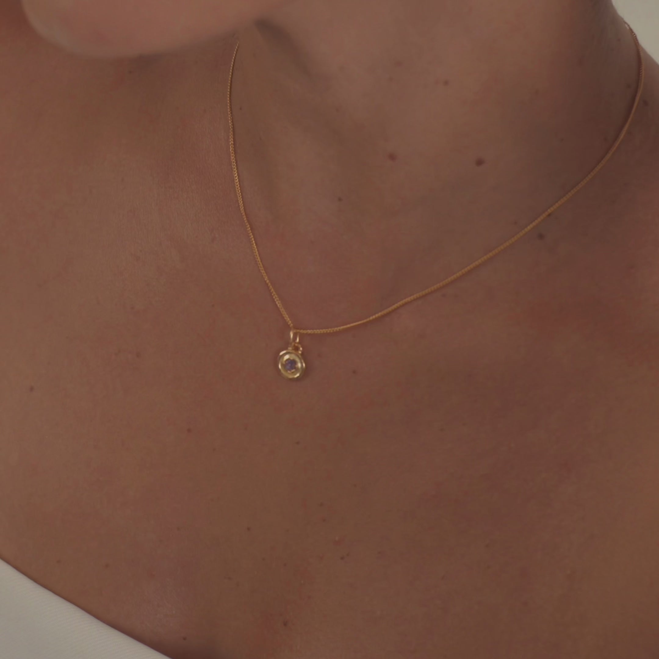 A model wearing an elegant amethyst birthstone necklace, highlighting the deep purple gemstone's natural sparkle.