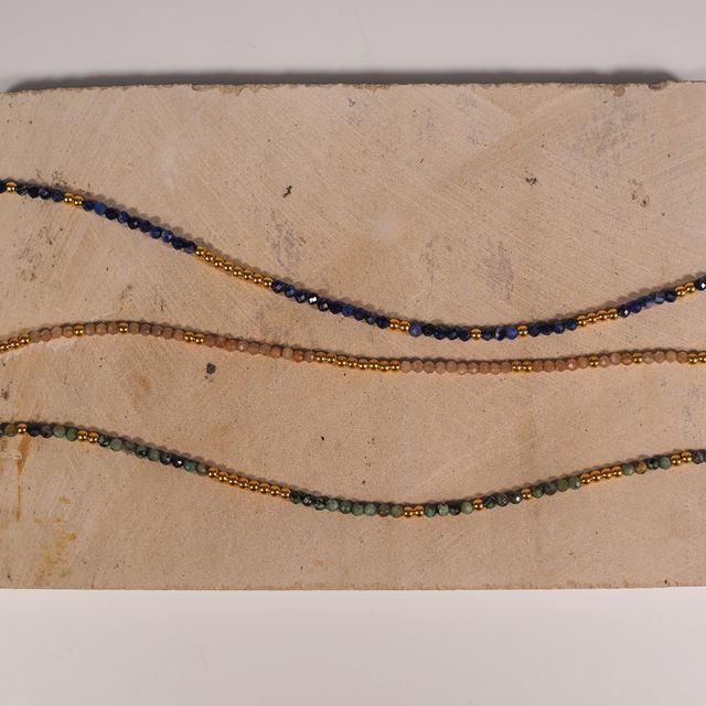 Jewelry product photo featuring three gemstone necklaces on a pastel pink textured surface