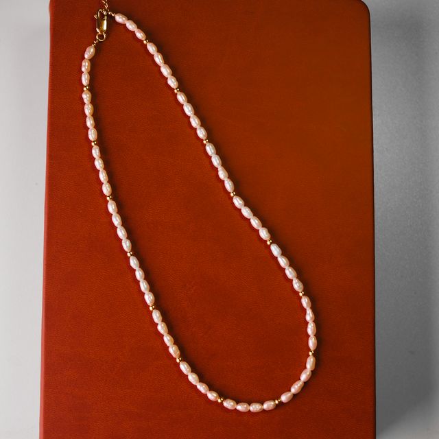 White pearl necklace with gold setting showcased on vibrant red fabric