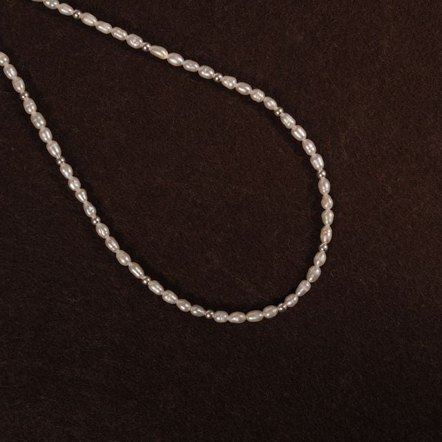 Classic pearl necklace with silver details arranged on deep red fabric