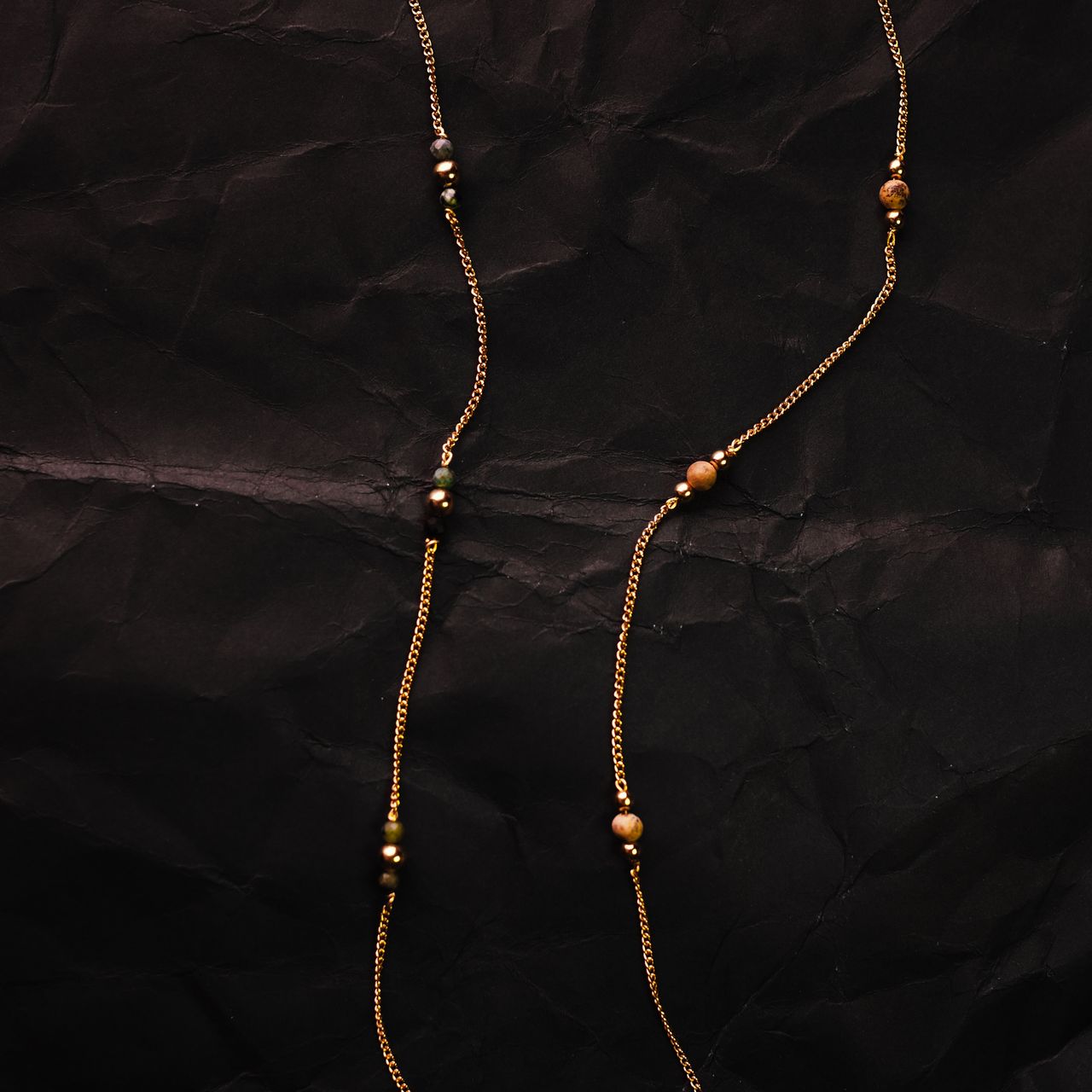 two necklaces lay on black paper by luna rose
