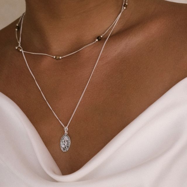 two layered silver necklaces on her 