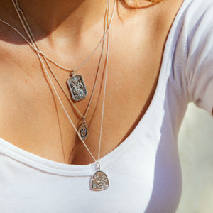 a woman with white tees wearing three layered necklaces 