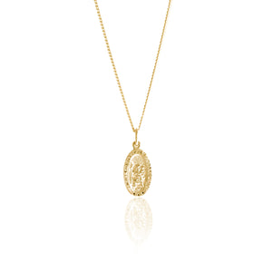 A gold necklace with an oval pendant featuring a raised religious figure design, displayed against a white background.