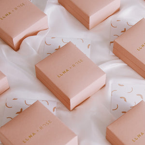 Several pink gift boxes labeled "Luna & Rose" with patterned cards scattered around them.