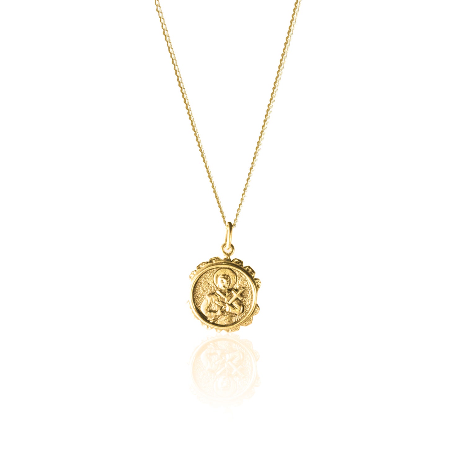 A gold necklace with a round pendant featuring a raised religious figure design, displayed against a white background.